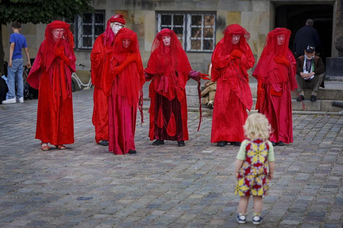 A child looking at costumed protesters during a demonstration at Christiansborg Palace Square in Copenhagen, Denmark, June 18, 2025.