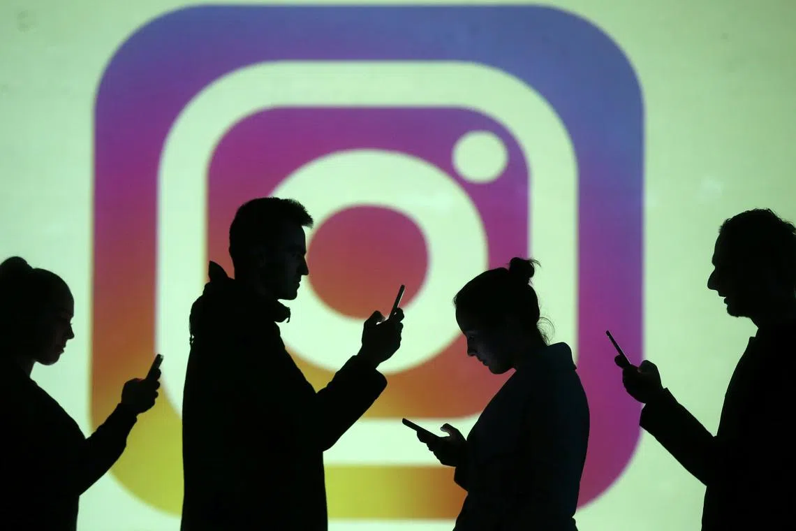 FILE PHOTO: Silhouettes of mobile users are seen next to a screen projection of Instagram logo in this picture illustration taken March 28, 2018.  REUTERS/Dado Ruvic/Illustration/File Photo