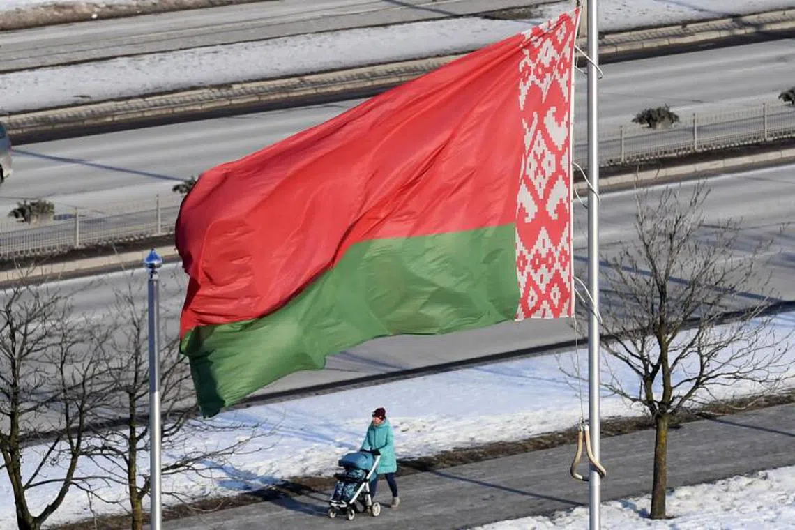 (FILES) A woman pushes a stroller under the Belarus' national flag in Minsk on January 23, 2019. (Photo by Kirill KUDRYAVTSEV / AFP)