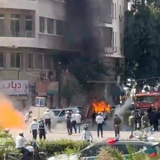 Emergency personnel work as smoke and fire rise at the site where explosive devices blew up near a hotel where French President Emmanuel Macron was meant to be staying, in Damascus, Syria, in this screengrab obtained from a video, July 7, 2026. REUTERS/Yamam Al Shaar