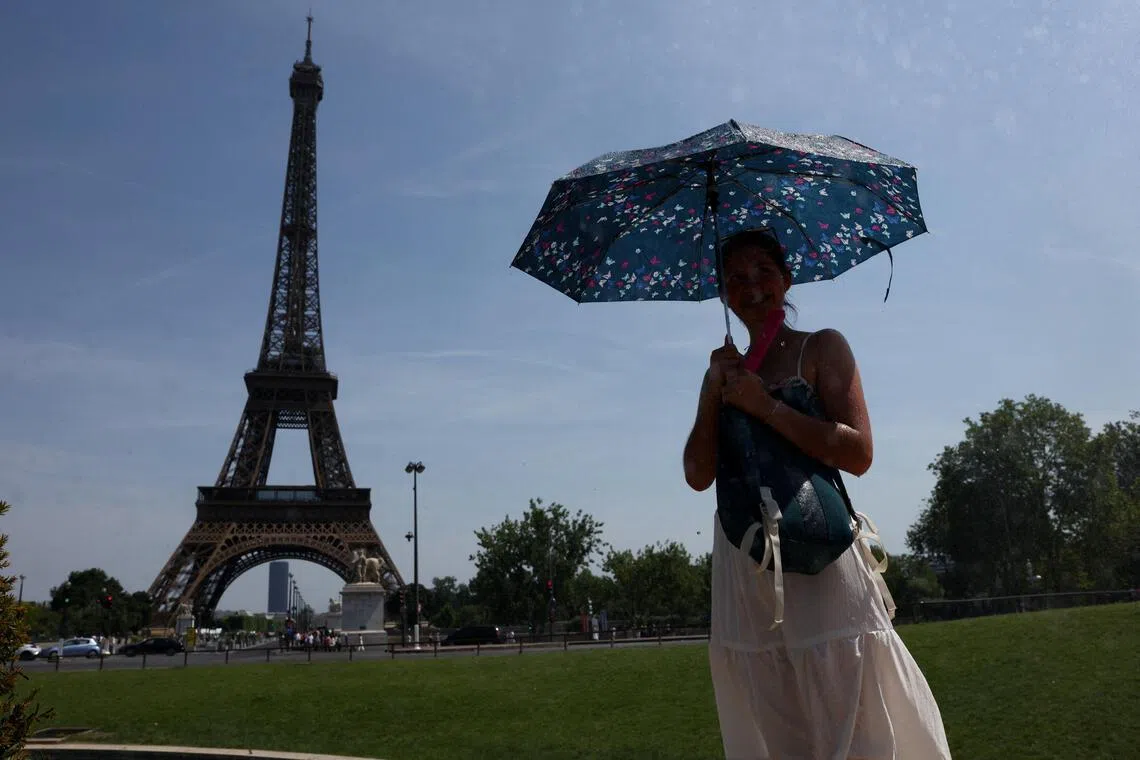 A person shelters under an umbrella by the Eiffel Tower during high temperatures amid a heatwave in Paris, France, June 27, 2026. REUTERS/Tom Nicholson