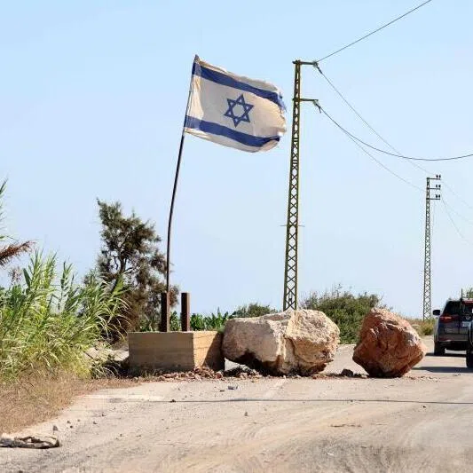 Media convoy vehicles driving past an Israeli flag fluttering along a road in the southern Lebanese area of Naqura on July 20.