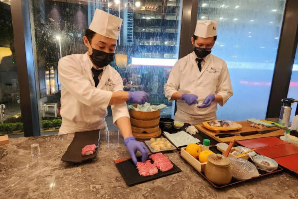 Kampachi's Chef Yusuke Ishigami (left) and Chef Bernard Chiah preparing wagyu nigiri aburi sushi (flame-seared sirloin sushi) and shime saba sushi (cured mackerel sushi).