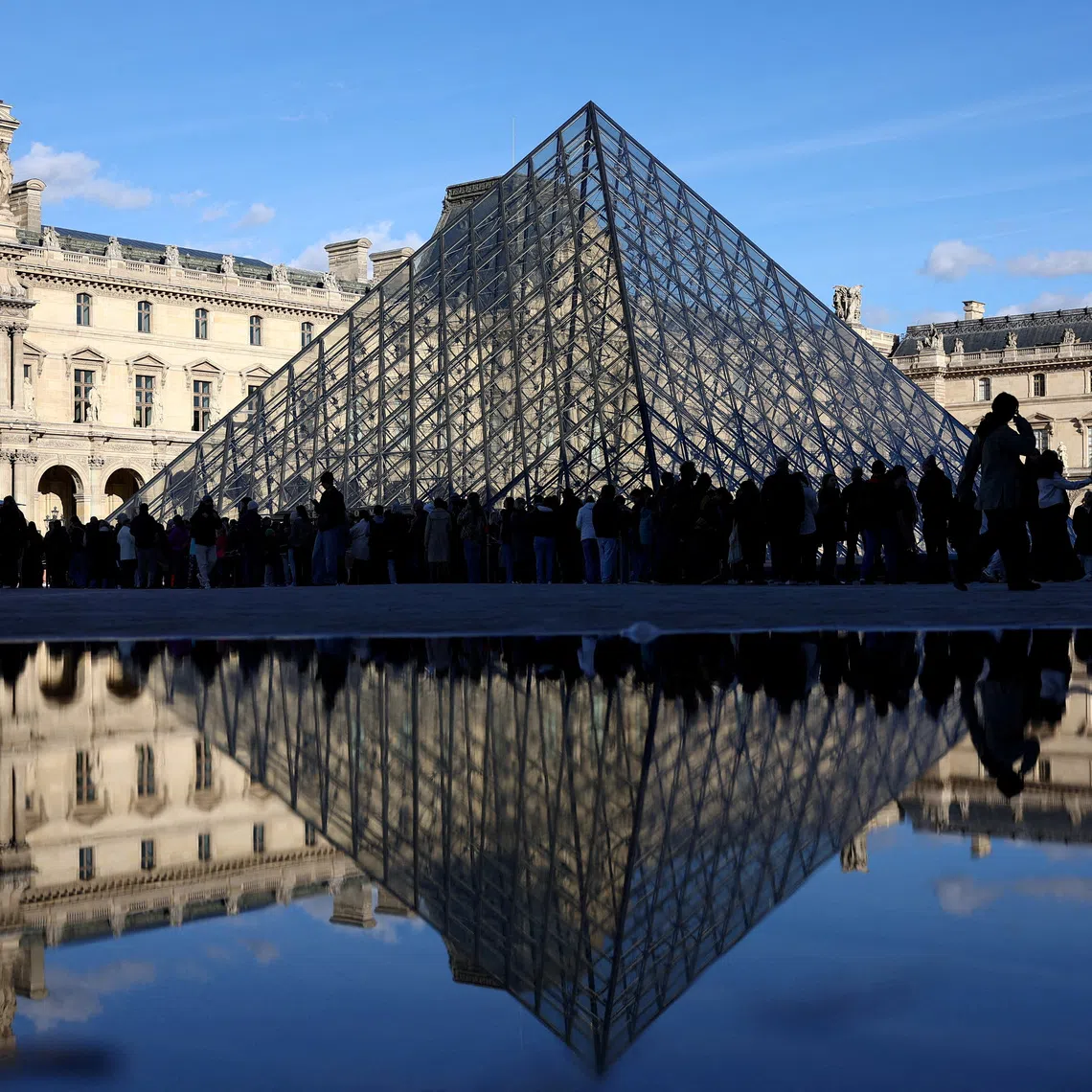FILE PHOTO: People stand outside the Louvre Museum, after French police arrested suspects in the Louvre heist case, in Paris, France October 26, 2025. REUTERS/Abdul Saboor/File Photo