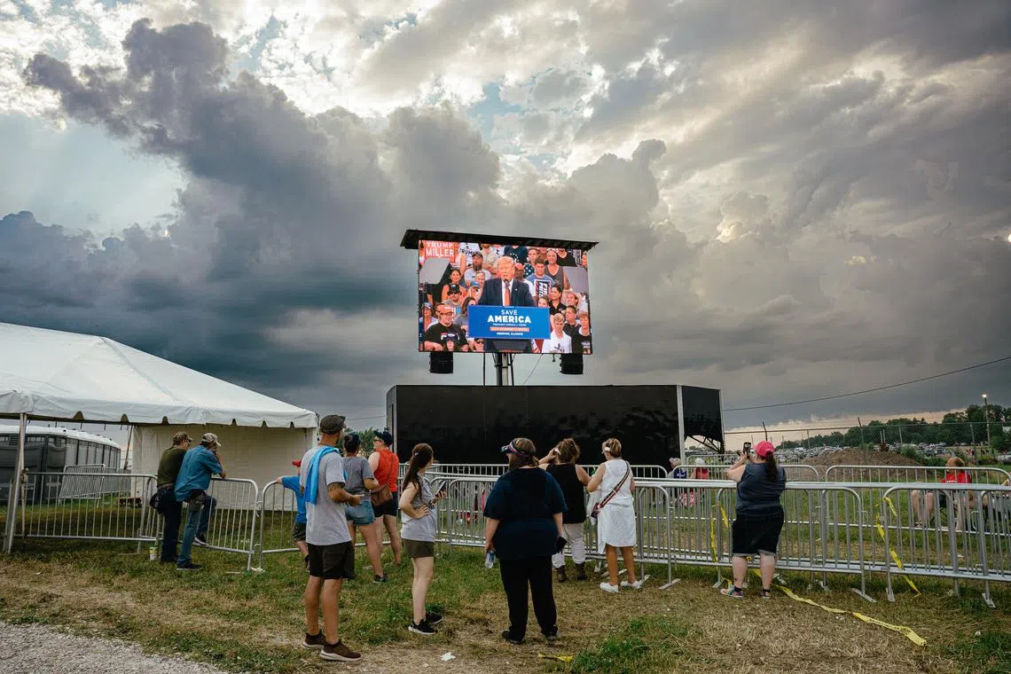 FILE — People watch a video feed of former President Donald Trump at a rally outside Quincy, Ill., June 25, 2022. Republicans may still win the House, but an underwhelming showing has the GOP wrestling with what went wrong: Was it bad candidates, a bad message or Trump? (Jamie Kelter Davis/The New York Times)