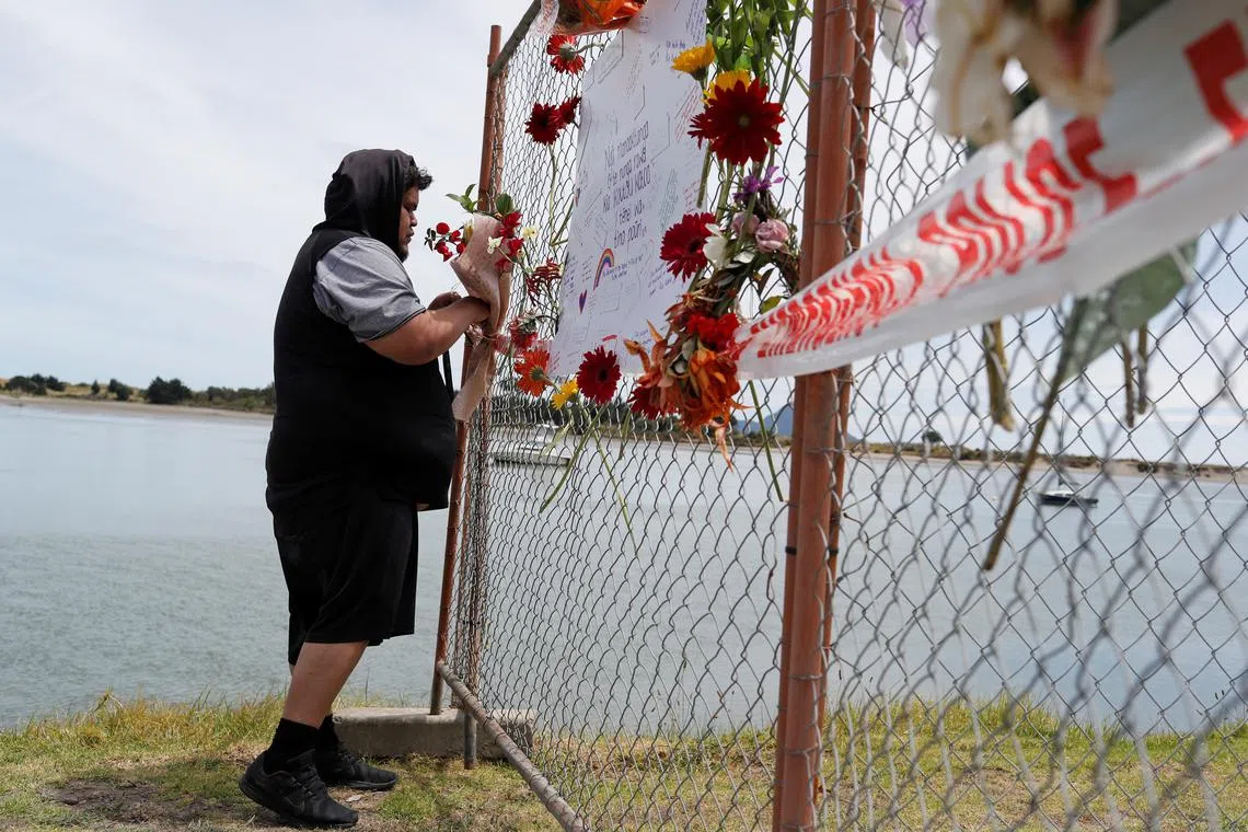 FILE PHOTO: A man offers flowers at a memorial at the harbour in Whakatane, following the White Island volcano eruption in New Zealand, December 11, 2019. REUTERS/Jorge Silva/File Photo