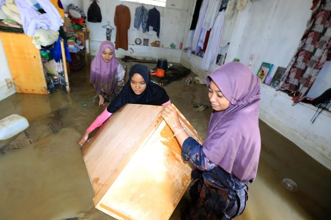 A group of women tries to salvage what is left of their belongings from their home in Aceh, Indonesia.
