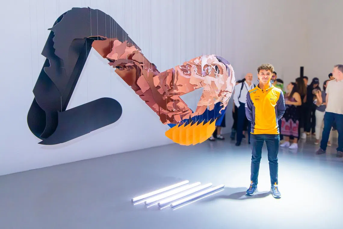 Formula One racer Lando Norris stands next to the three-dimensional sculpture that changes between his face and the Airwallex logo.