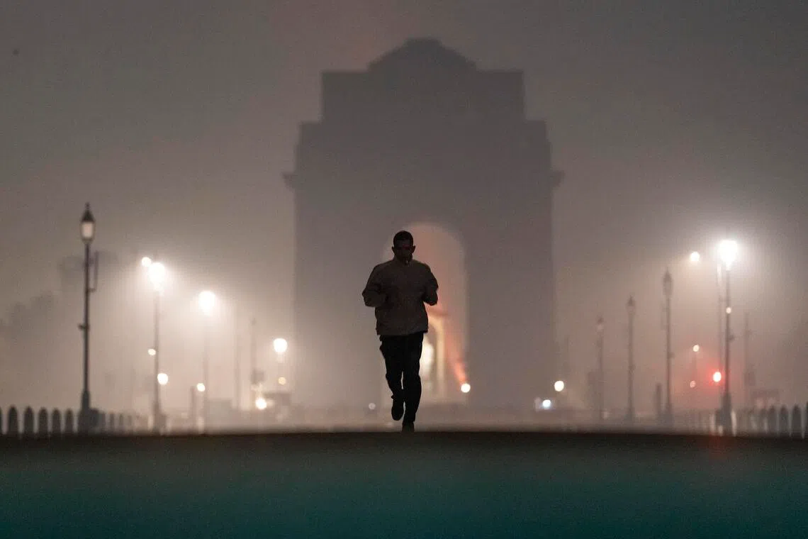 An early morning jogger and India Gate, a national war memorial, shrouded in a haze caused in part by air pollution in New Delhi, Nov. 24, 2025. India is rising as an economic and technological world power, but air pollution is turning its capital into a lethal gas chamber. (Anindito Mukherjee/The New York Times)