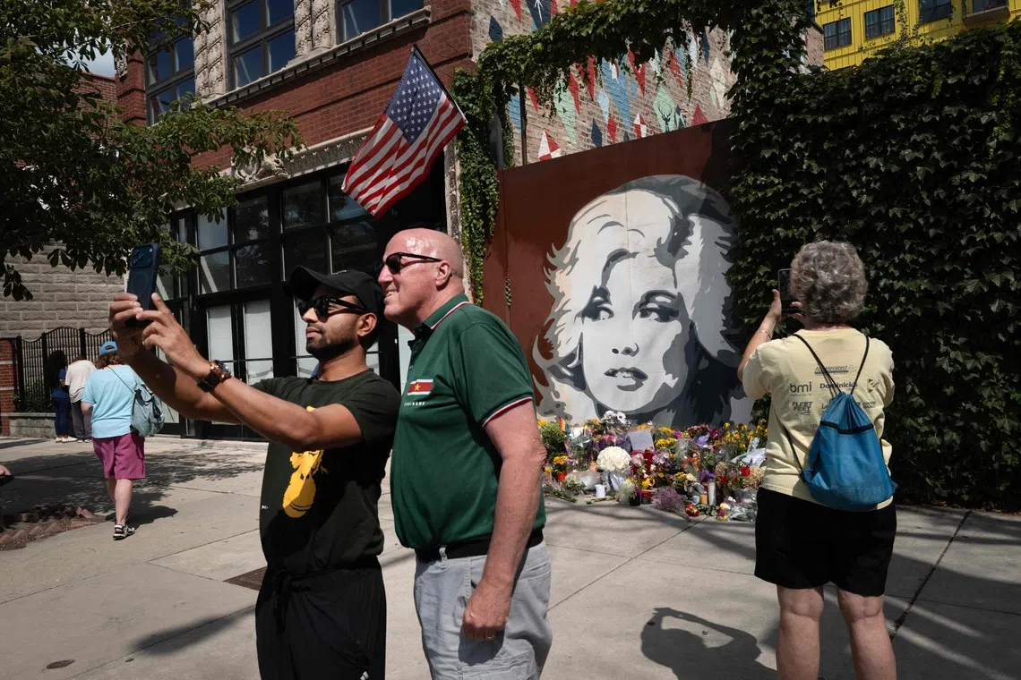 Fans of Dolly Parton visit a mural featuring her likeness in Chicago on Aug 26.