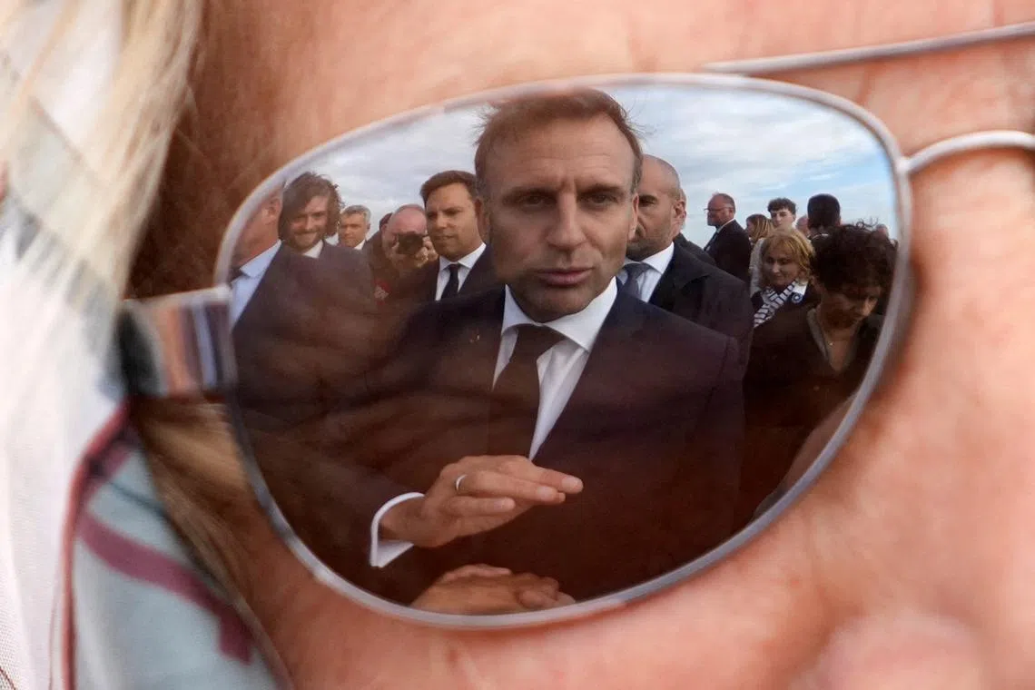 French President Emmanuel Macron is reflected on a resident's glasses on the day of a ceremony commemorating Charles de Gaulle's World War II resistance call in the Ile de Sein, France, on June 18, 2024. 