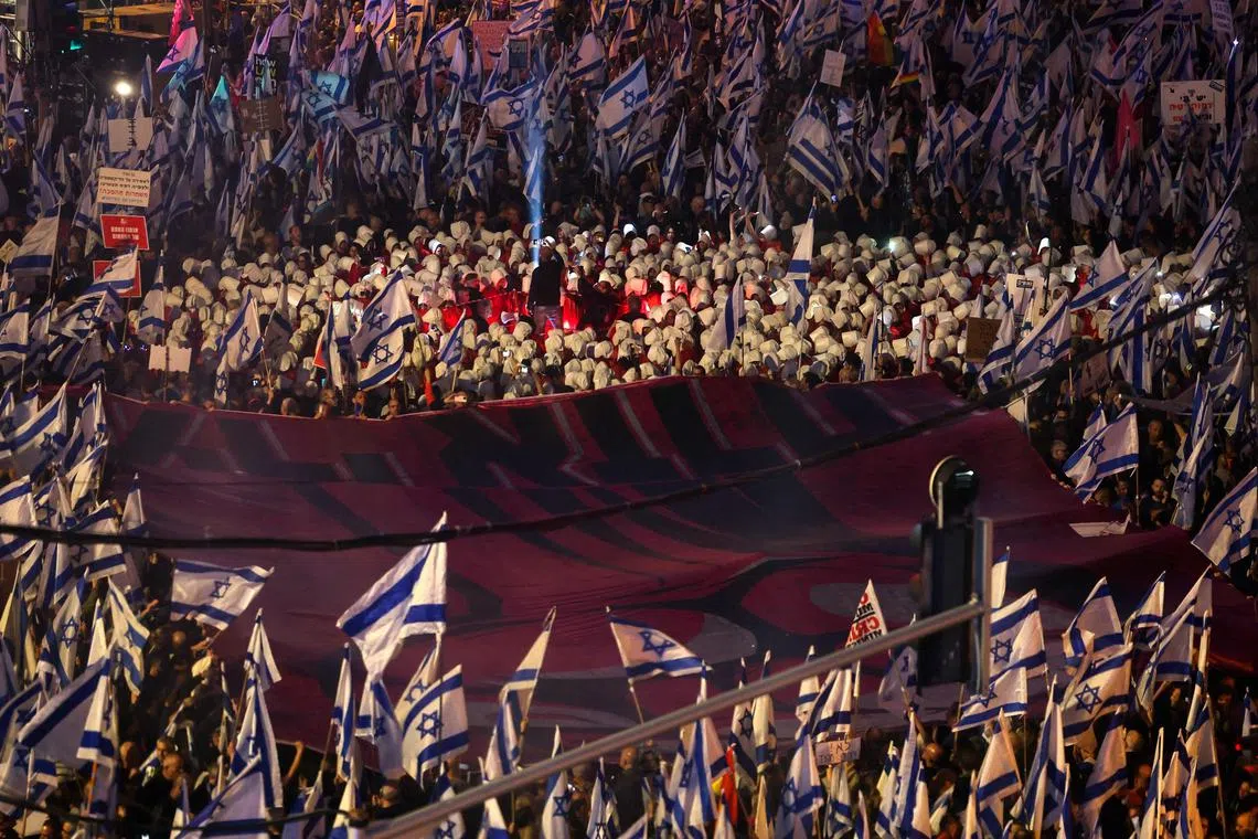 Demonstrators lift national flags during a protest against the Israeli government's controversial judicial reform bill in Tel Aviv.