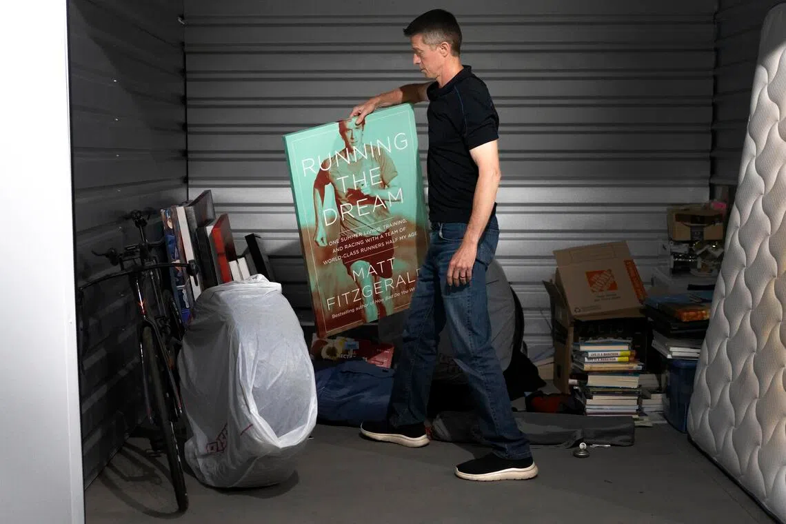 Matt Fitzgerald holds a poster of the cover for his book, Running The Dream, at his storage unit in Flagstaff, Arizona, on June 28.