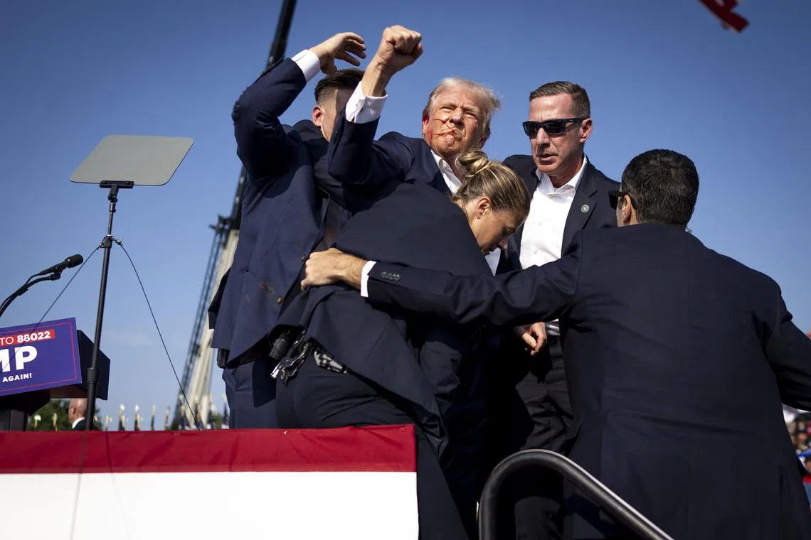 Secret service agents surround former President Donald Trump after being shot during a campaign rally in Butler, Pa, on Saturday, July 13, 2024. In video footage, everything was pandemonium. It was still images that defined the attack and its aftermath. (Doug Mills/The New York Times)