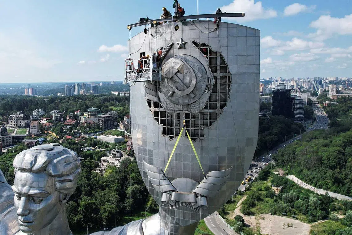 Workers dismount a Soviet emblem from the shield of the 'Motherland' monument, amid Russia's attack on Ukraine, at a compound of the World War II museum in Kyiv, Ukraine, Aug 1, 2023. 
