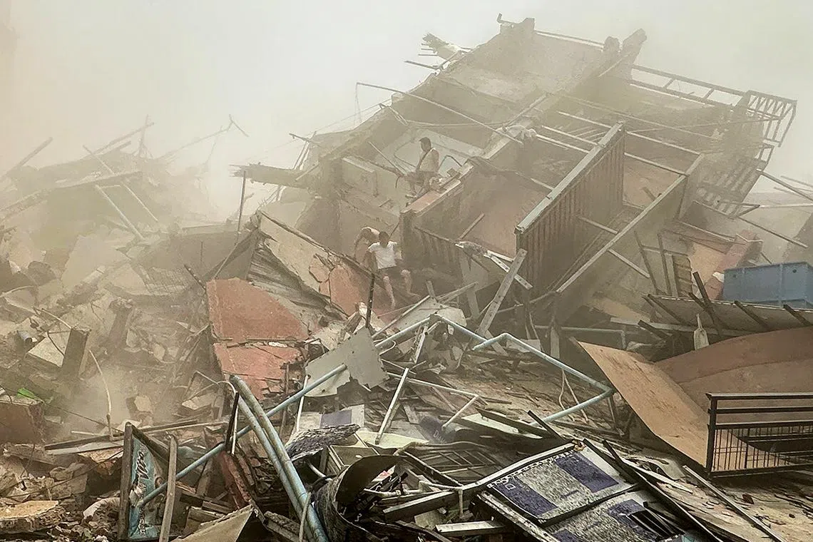 TOPSHOT - People inspect the debris of a collapsed building in Mandalay on March 28, 2025, after an earthquake. A powerful earthquake killed more than 20 people across Myanmar and Thailand on March 28, toppling buildings and bridges and trapping over 80 workers in an under-construction skyscraper in Bangkok. (Photo by AFP)