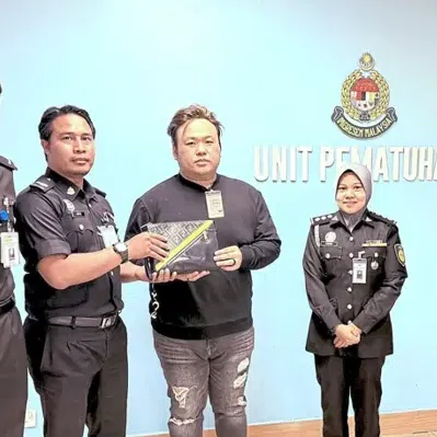 Singaporean Tan Zheng Guang (centre) with the immigration officers who helped him return his bag.