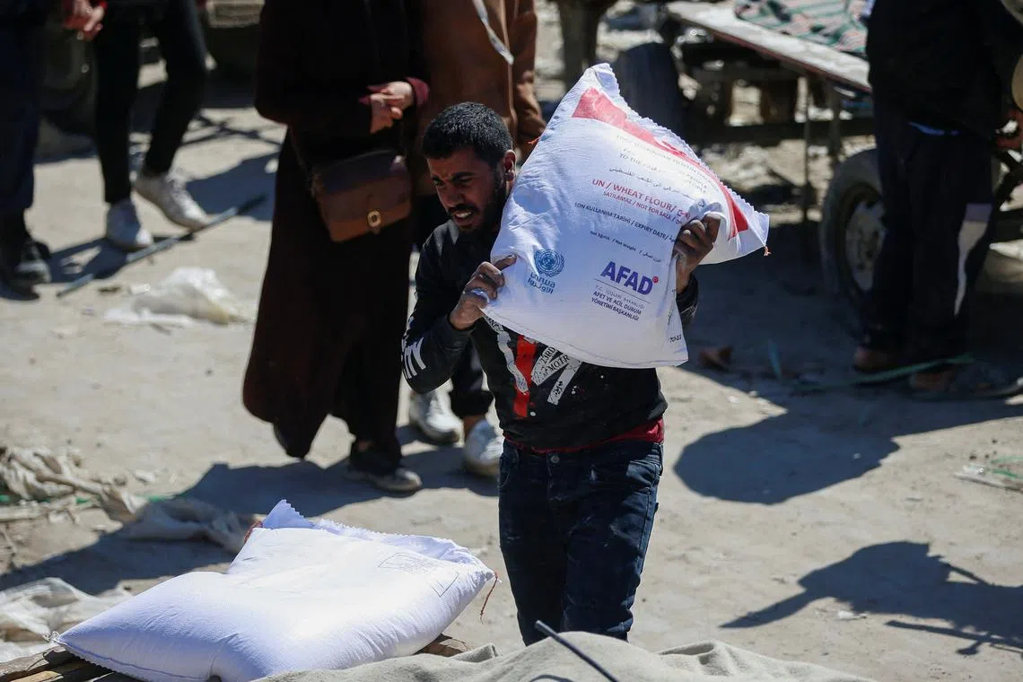FILE PHOTO: A man carries a sack as Palestinians gather to receive aid provided by UNRWA including food supplies, after Israel says it has ceased entry of humanitarian aid into Gaza, outside a distribution center, at Jabalia refugee camp in northern Gaza Strip, March 2, 2025. REUTERS/Mahmoud Issa/File Photo