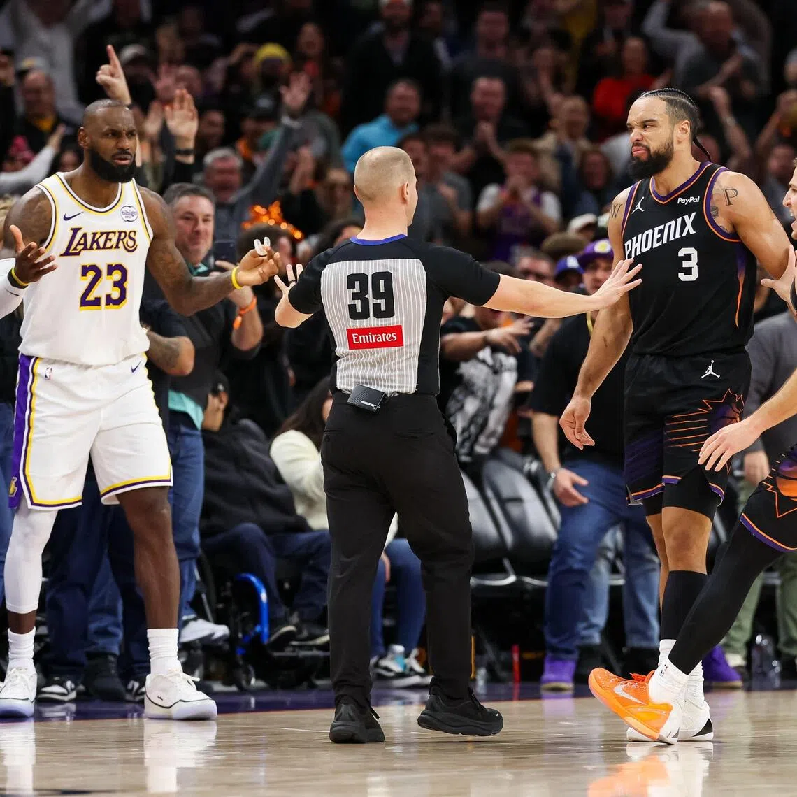 An official comes between Lebron James of the Los Angeles Lakers and Dillon Brooks of the Phoenix Suns during the second half of the NBA game at Mortgage Matchup Center on Dec 14, 2025. The Lakers prevailed 116-114, while Brooks was ejected in the dying seconds.