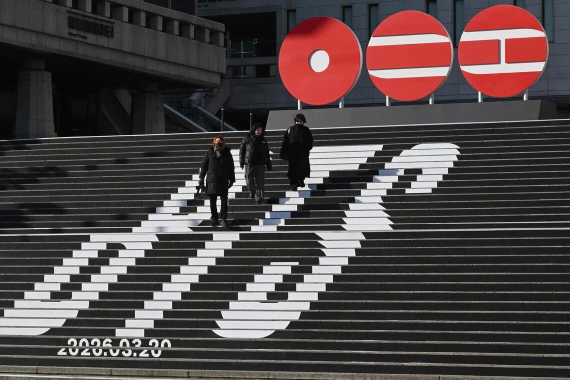 Pedestrians walk along the stairs displayed with the logo of BTS' 2026 album and release date at Gwanghwamun Square in Seoul on Jan 14, 2026. 