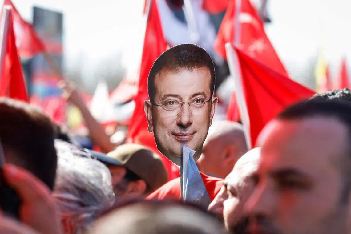 A protestor holds a cut out of Istanbul's arrested mayor Ekrem Imanoglu during a rally.