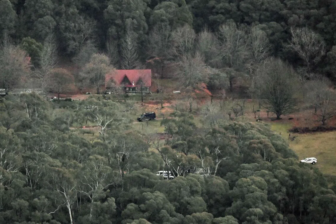 An armoured police vehicle parks outside a property as the search intensifies for a fugitive linked to the murder of two police officers in Porepunkah.
