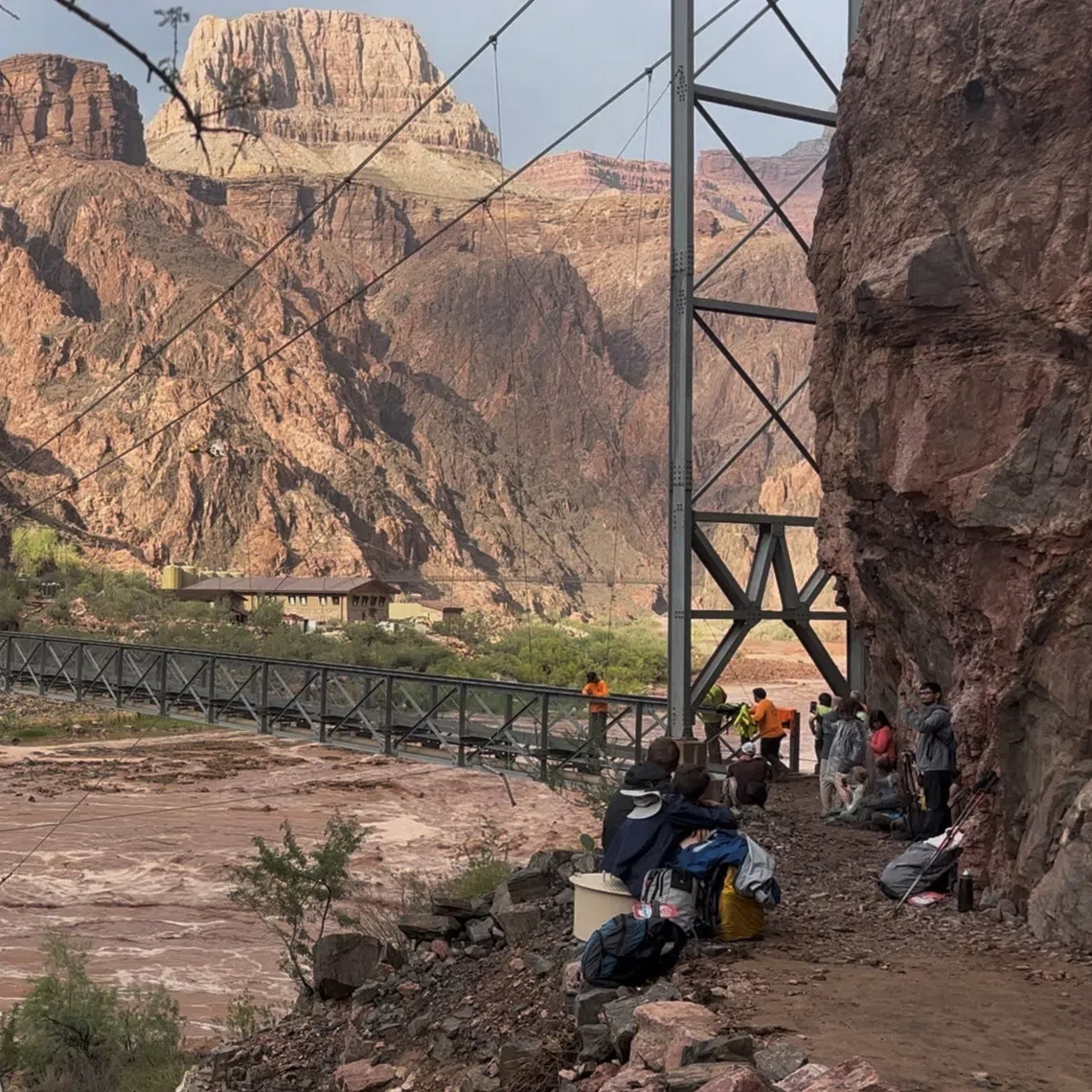 People wait near a bridge as a helicopter flies nearby amid flash flooding in the Grand Canyon National Park, Arizona, on Aug 29.