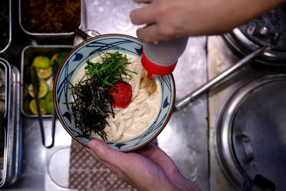 An employee prepares a bowl of udon noodles at a Marugame Seimen restaurant in Tokyo.