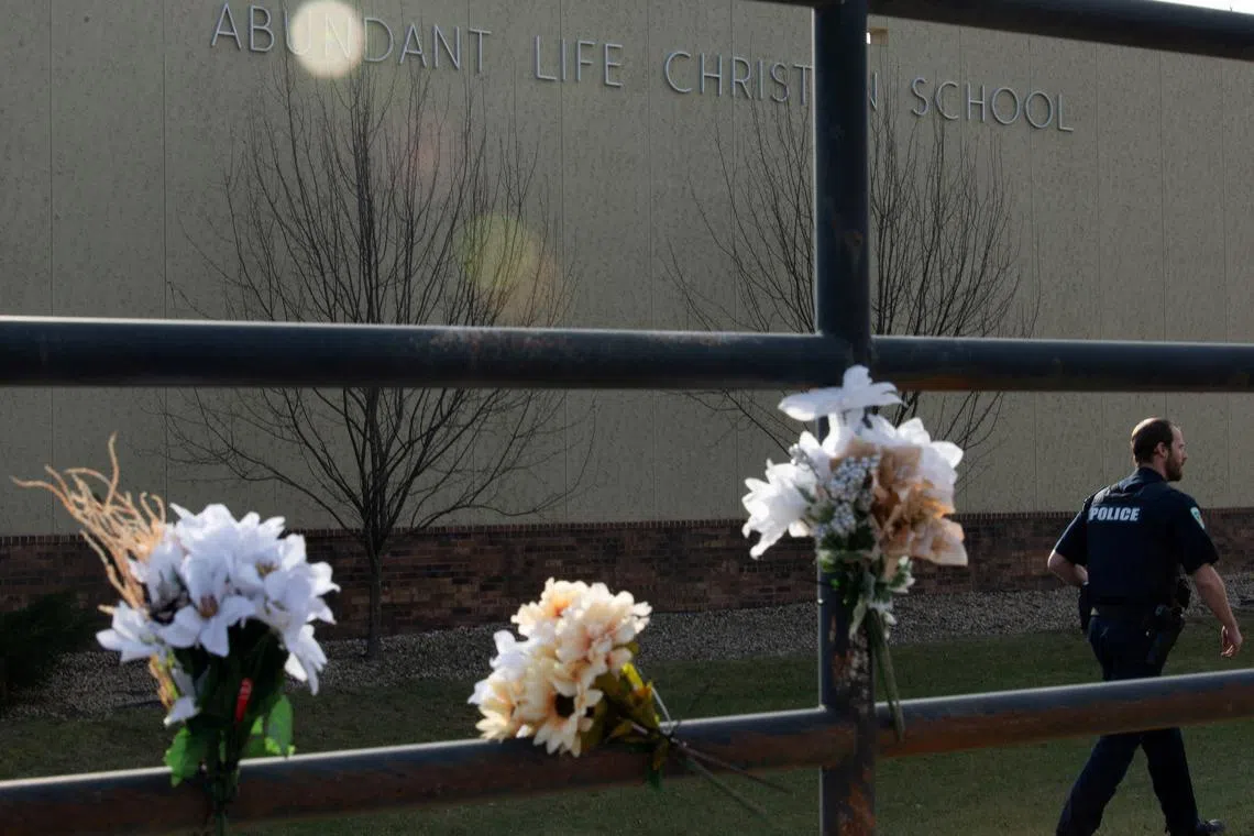 A police officer passes flowers left in memory of victims a day after a shooting at Abundant Life Christian School, in Madison, Wisconsin, U.S. December 17, 2024.  REUTERS/Cullen Granzen