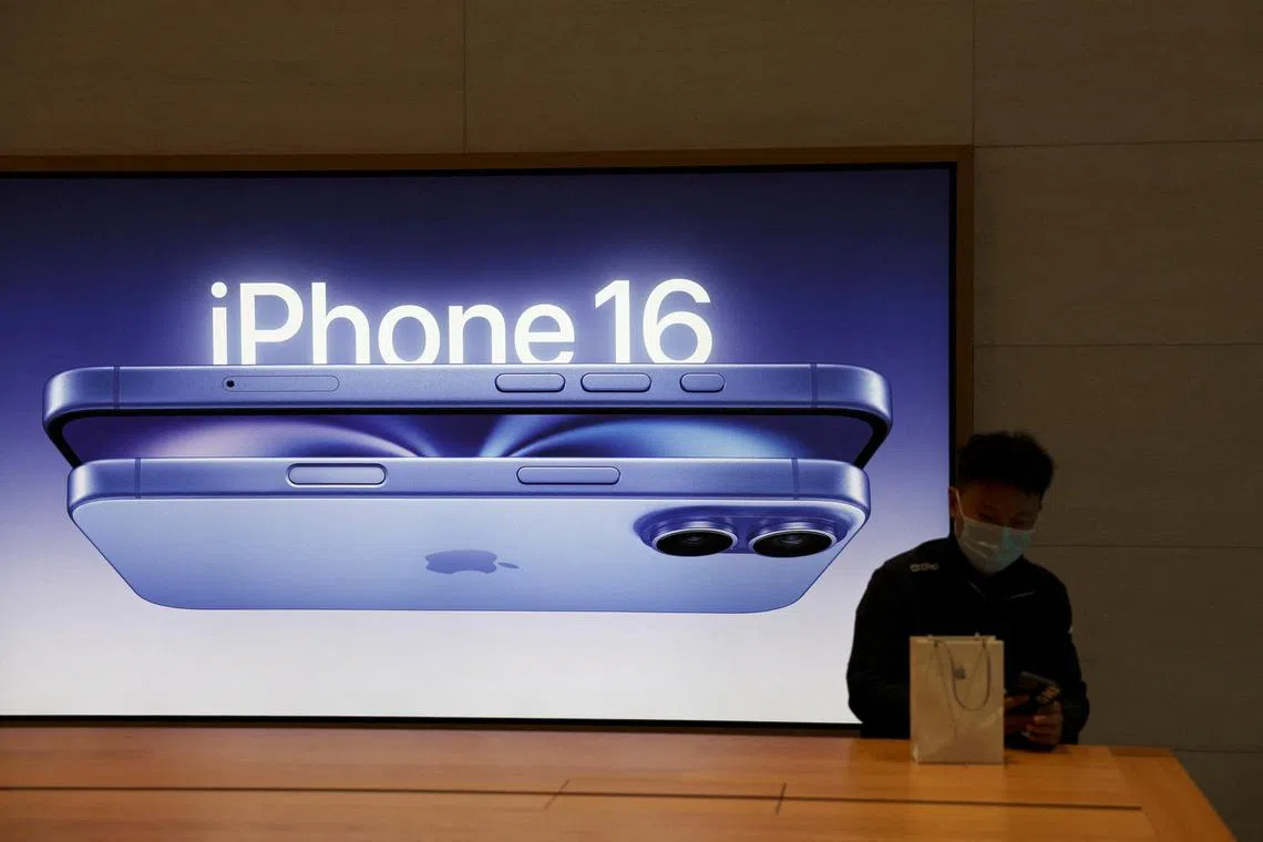 A man sits next to an iPhone 16 advertisement as the new iPhone 16 series smartphones go on sale at an Apple store in Beijing on Sept 20. 