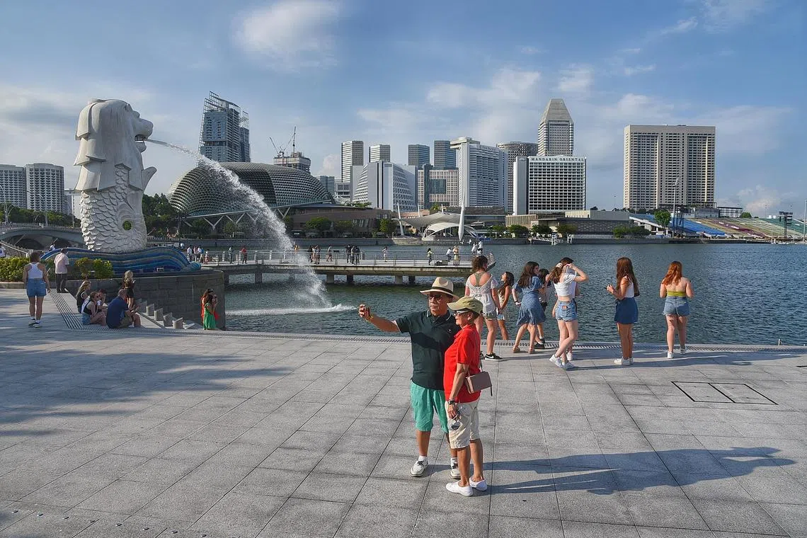 Pixgeneric/Generic picture of a very long harsh contrasty shadow casting on tourists at the Merlion Park in the late afternoon on 18 May 2022. Story of hot weather pictures and climate chnge