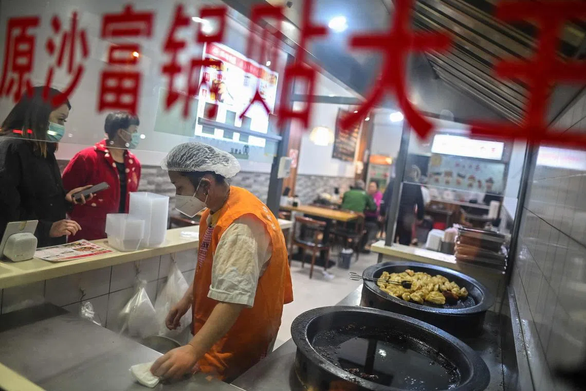People buy food in a small restaurant in the Jing'an district in Shanghai, on November 3, 2022. (Photo by Hector RETAMAL / AFP)