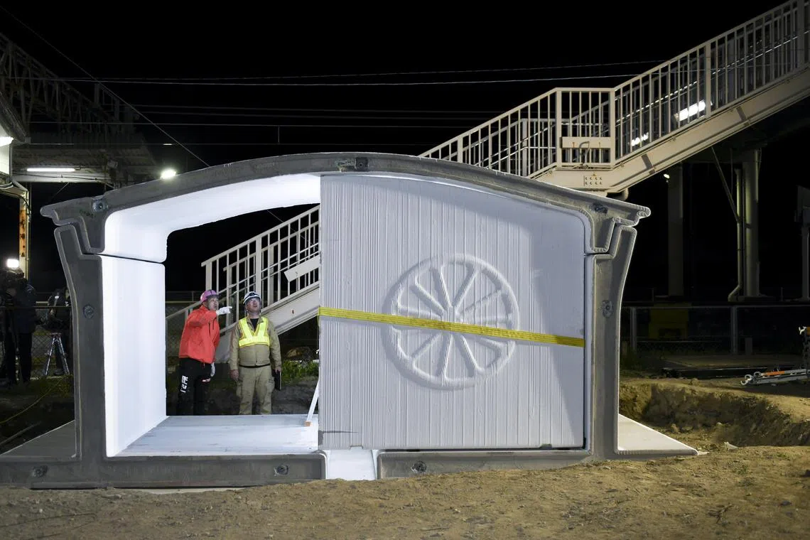 Workers assemble the new Hatsushima train station, which is made from 3D-printed components, in Arida, Japan, March 26, 2025.