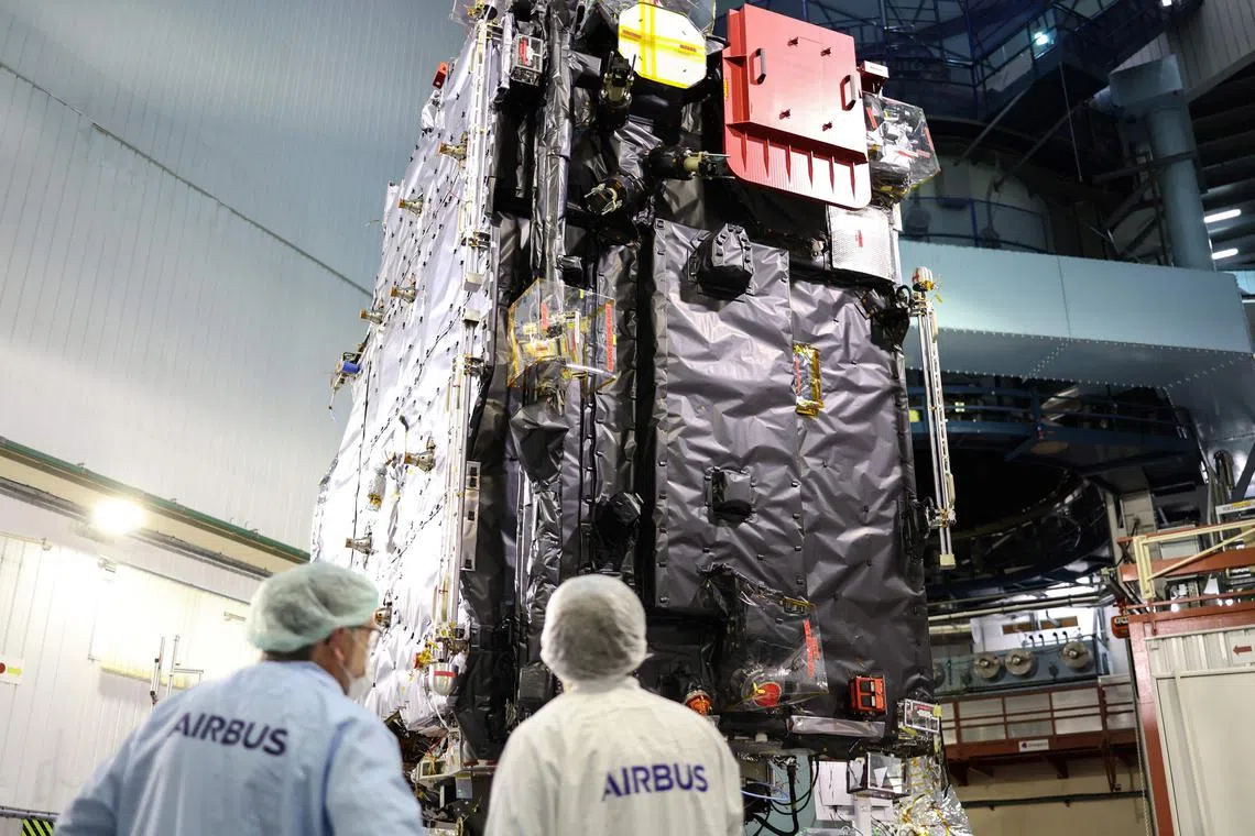 (FILES) Engineers work around the ESA's (European Space Agency) "Juice" probe during its unveiling for media in Toulouse, southwestern France on January 20, 2023, a few days ahead of its departure to Kourou space center. A spacecraft that launched in April 2023 will slingshot back around Earth and the Moon in August 2024 in a high-stakes, worlds-first manoeuvre as it pinballs its way through the Solar System to Jupiter. (Photo by Charly TRIBALLEAU / AFP)