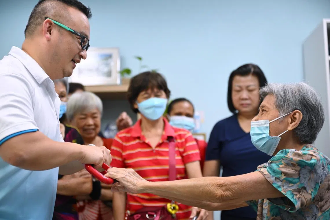 Co-founder of SG Assist Greg Tan (left) demonstrating how to use the Handy Handle to lift a patient to elderly guests during the launch of the Age Living Lab.
