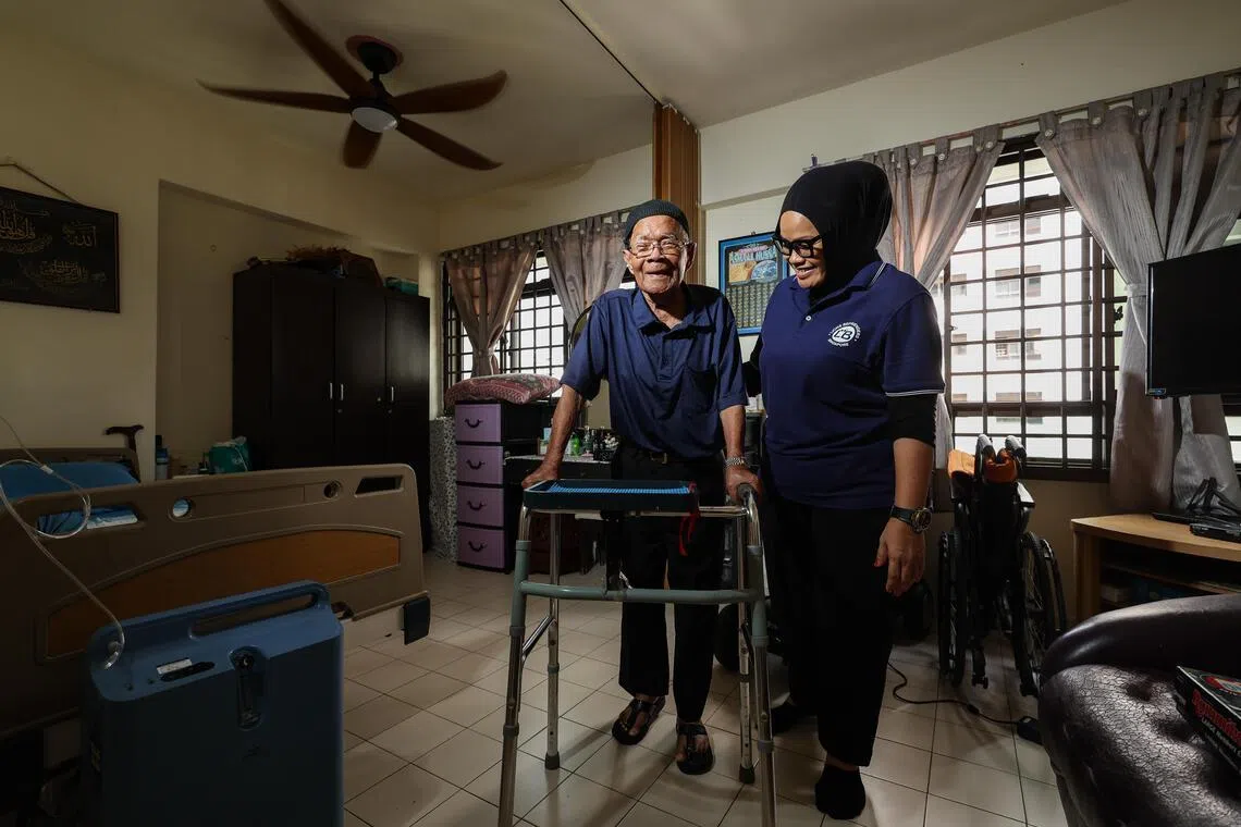 Radiana Ahmad (right), 49, healthcare assistant, tending to Abu Alias Man, 89, at his home in Clementi. Despite working in an AI-resilient sector, she feels pressure to keep up with the technology.