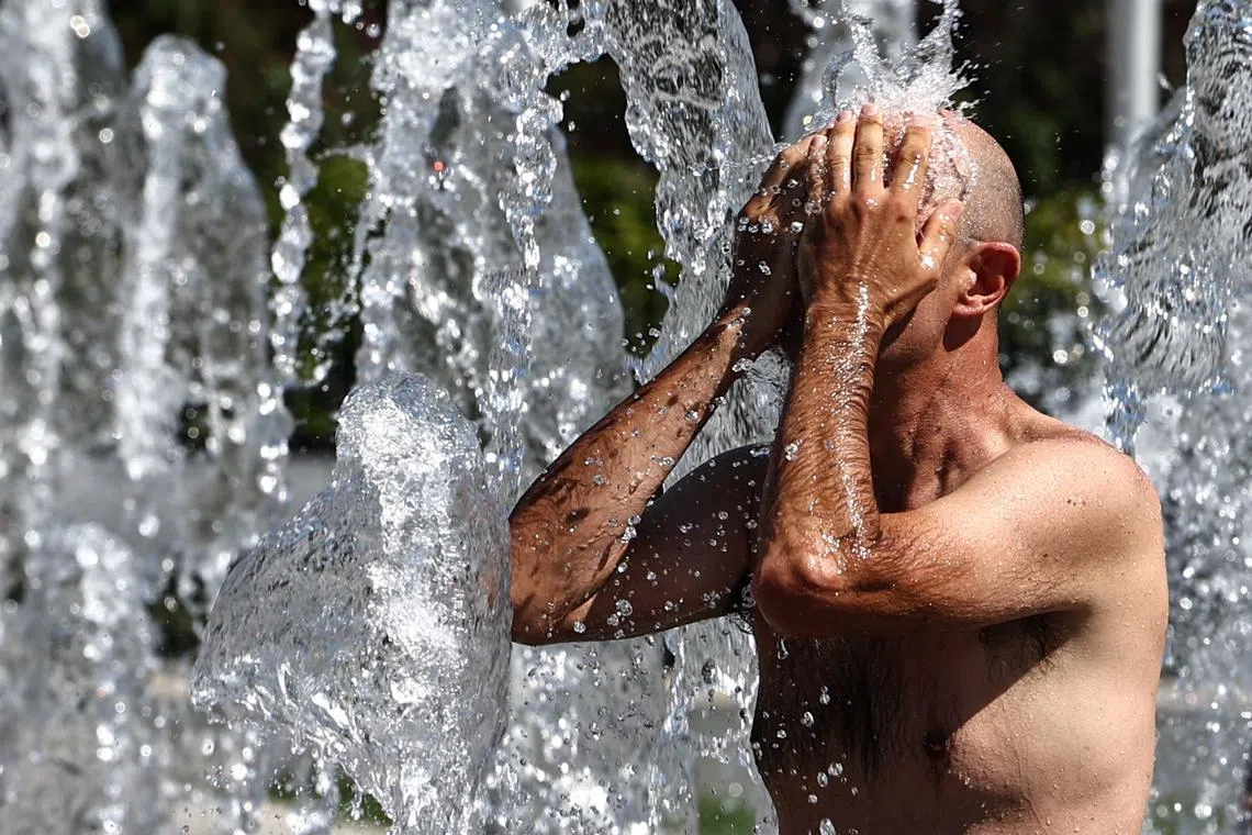 A man cooling off in a public fountain in Colmar, France, amid a heatwave on Aug 21.