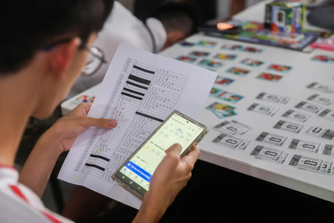 Zelthan Goh, 19, cross-referencing his physical Panini sticker trading list with an electronic list, to determine which stickers he did not have.