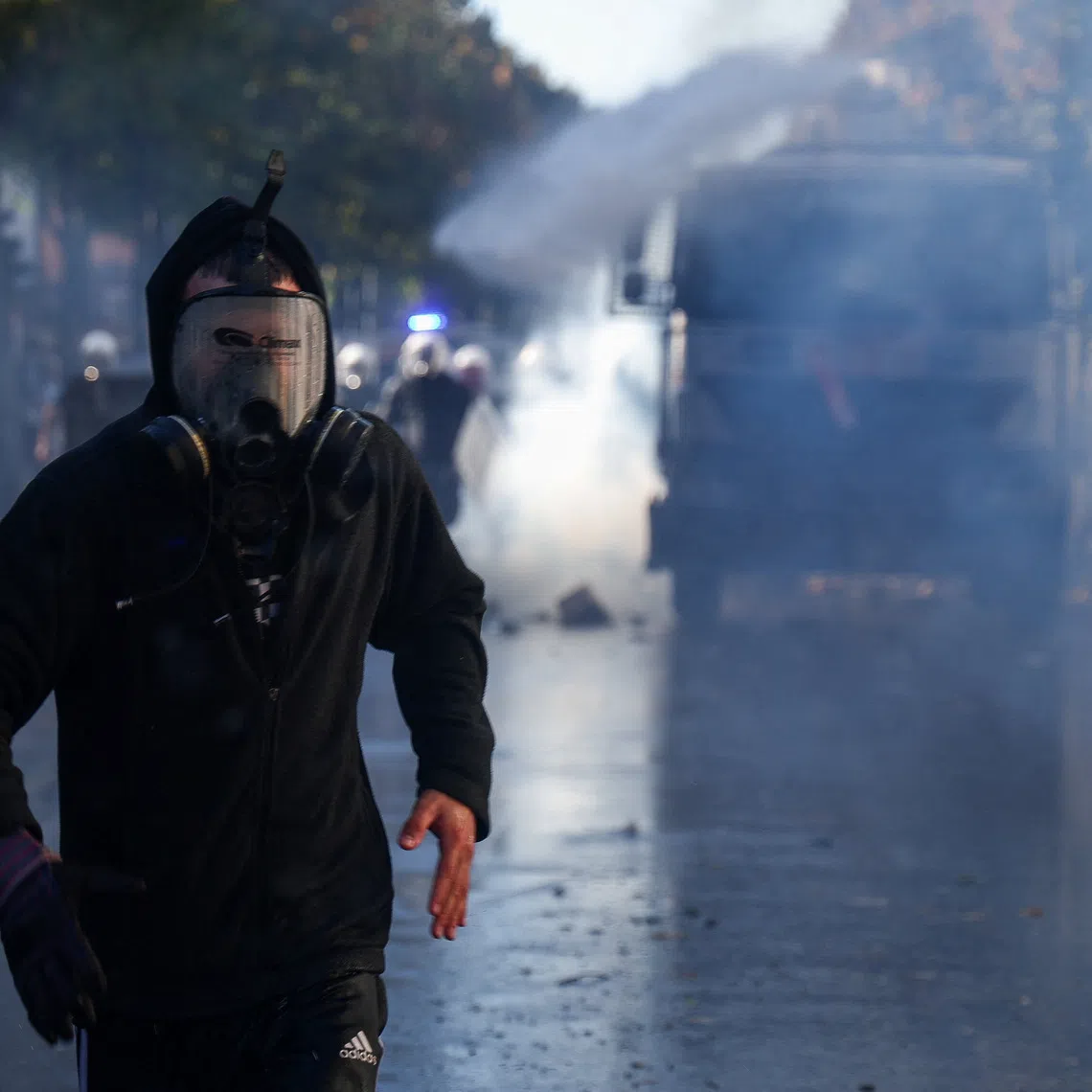 A demonstrator wearing a protective mask runs ahead of a water cannon truck during an anti-government protest by students in Tirana, Albania, October 16, 2026. REUTERS/Florion Goga