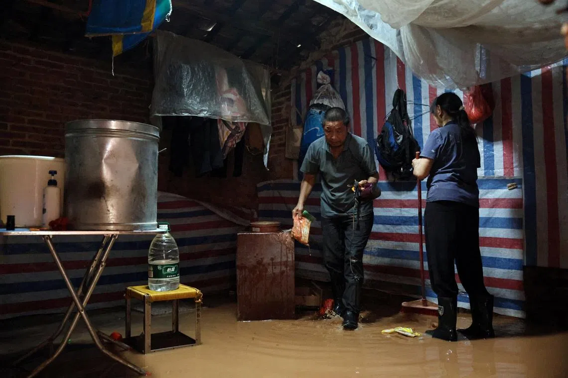 A resident moves his belongings in a flooded house after days of heavy rainfall in August 2025 in Qingyuan, Guangdong.