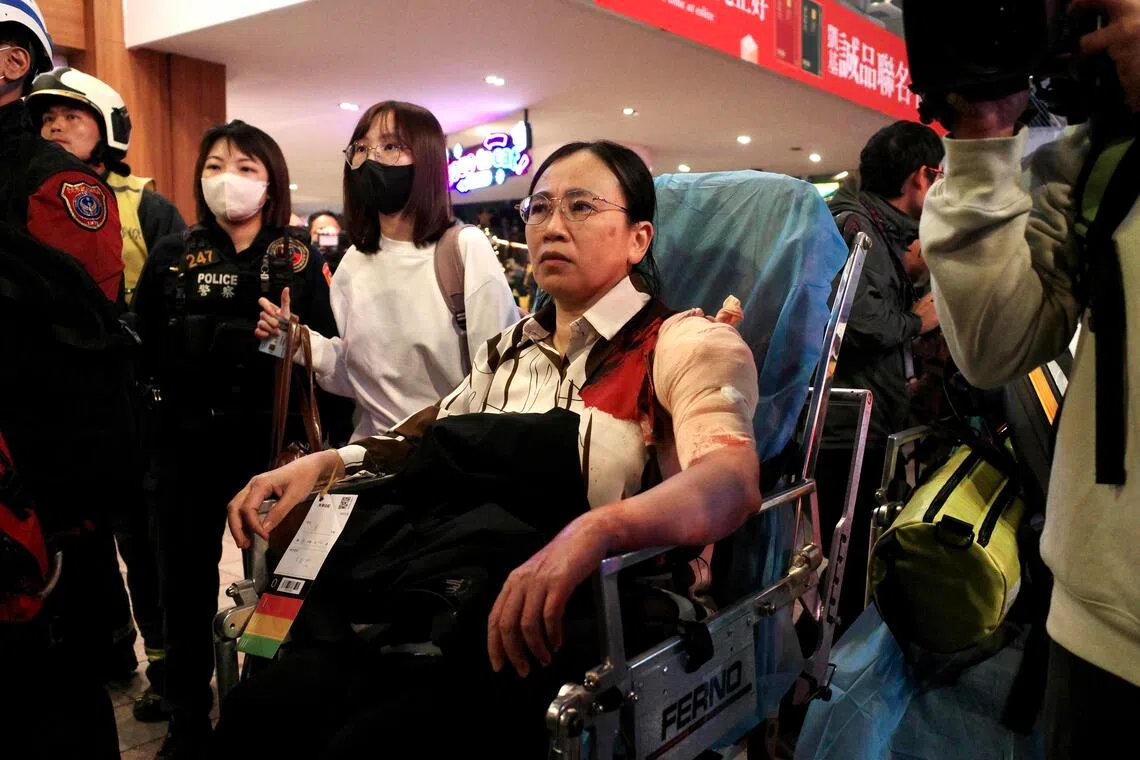 An injured woman in a bloodstained shirt being wheeled away from the main train station in Taipei, on Dec 19. 
