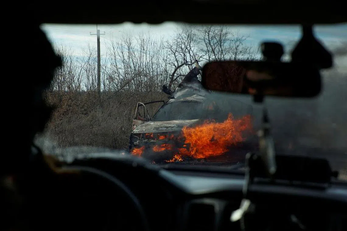 FILE PHOTO: Ukrainian servicemen move past a burning car hit by a kamikaze drone outside the front line town of Avdiivka, amid Russia's attack on Ukraine, in Donetsk region, Ukraine November 8, 2023. Radio Free Europe/Radio Liberty/Serhii Nuzhnenko via REUTERS/File Photo