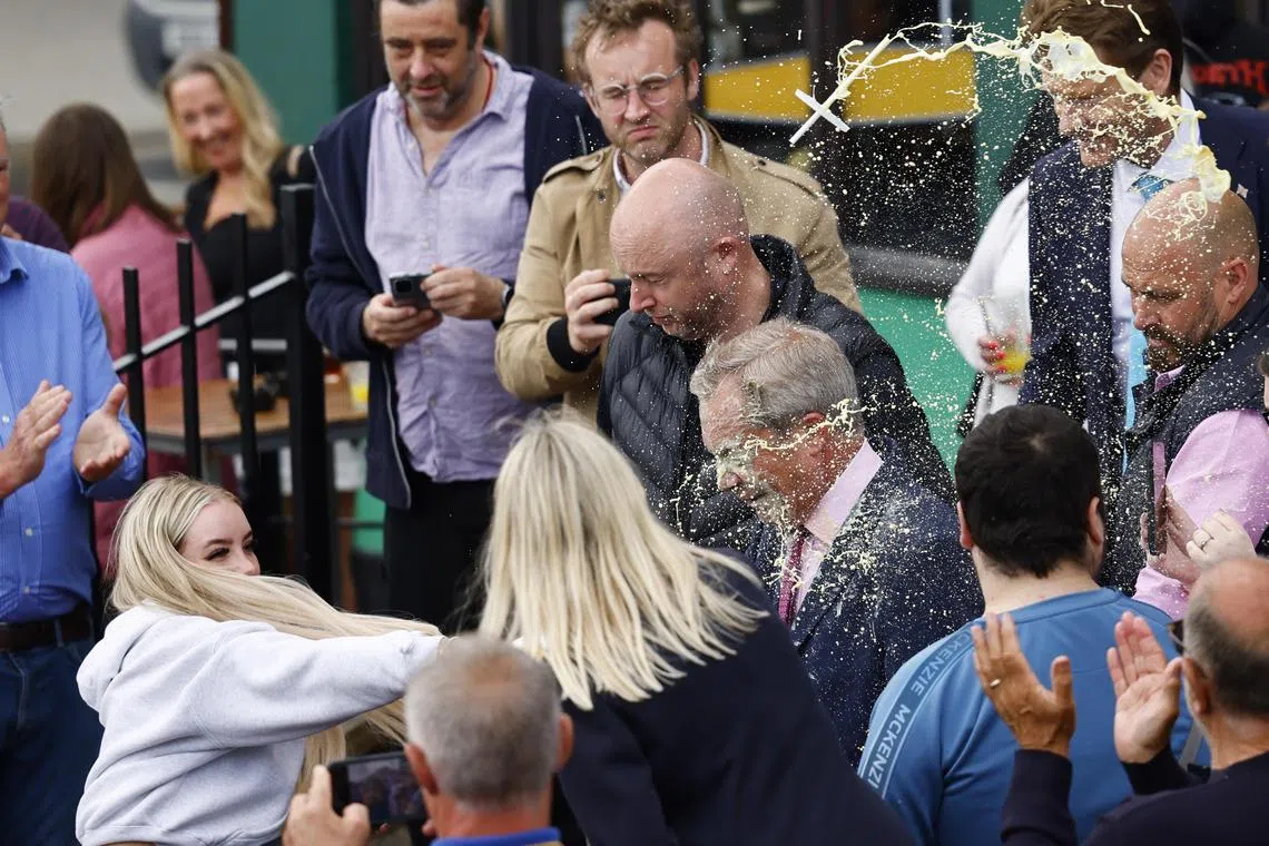 A young woman (left) throws a milkshake at Mr Nigel Farage, leader of the right-wing Reform UK party in Britain.