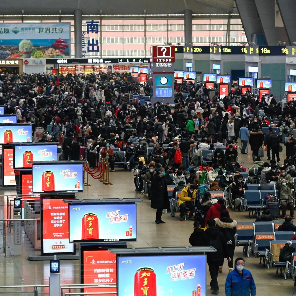 Passengers wait to check in at a railway station in Beijing on January 12, 2023, as the annual migration begins with people heading back to their hometowns for Lunar New Year celebrations. (Photo by WANG ZHAO / AFP)