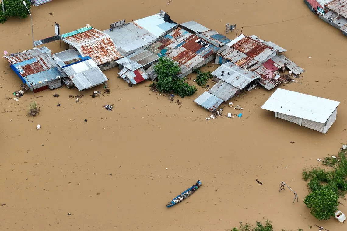 A resident paddling his boat in the flood waters past inundated houses in Tuguegarao City, Cagayan province, north of Manila, on Nov 10, 2025, after a river overflowed following heavy rains brought about by Super Typhoon Fung-wong. 