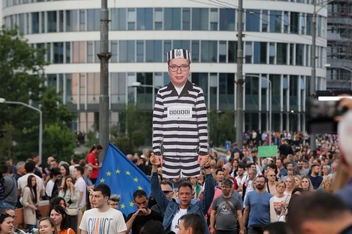 Political activist Petar Djuric (centre) holds a cardboard figure of Serbian President Aleksandar Vucic in a prison uniform. during a rally in Belgrade.