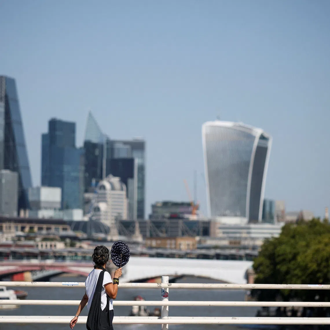 A woman walks across Waterloo Bridge, with the City of London financial district in the background, in London, Britain, August 13, 2026. REUTERS/Isabel Infantes/File Photo