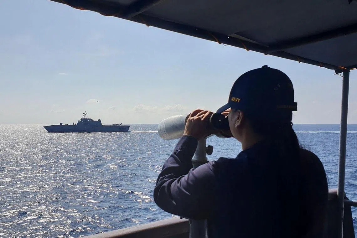 A member of the Philippine Navy conducts a bridge lookout aboard the BRP Gregorio Del Pilar to verify the USS Gabrielle Giffords (left).