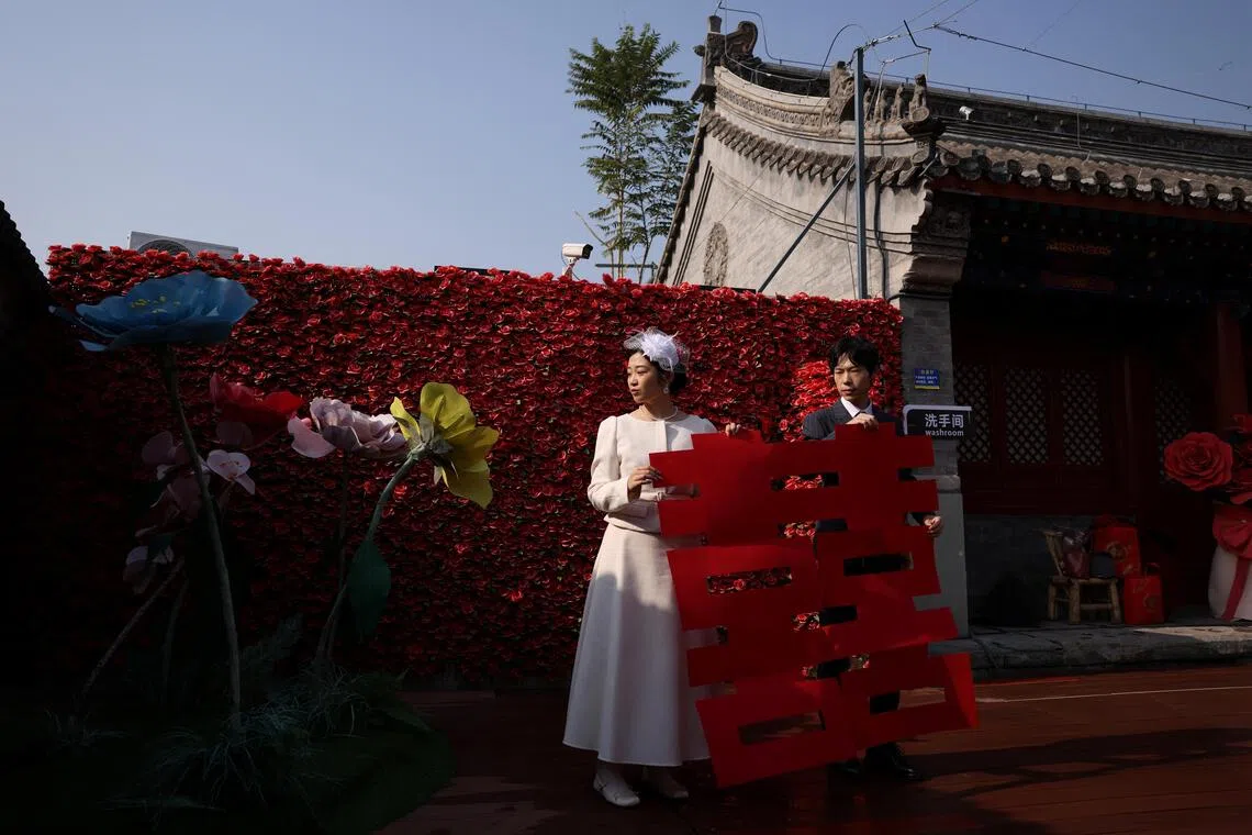 A newlywed couple holding a giant cut-out of the Chinese character Xi, which reads double happiness,   after they registered their marriage at the Huguo Guanyin Temple, in Beijing, China.