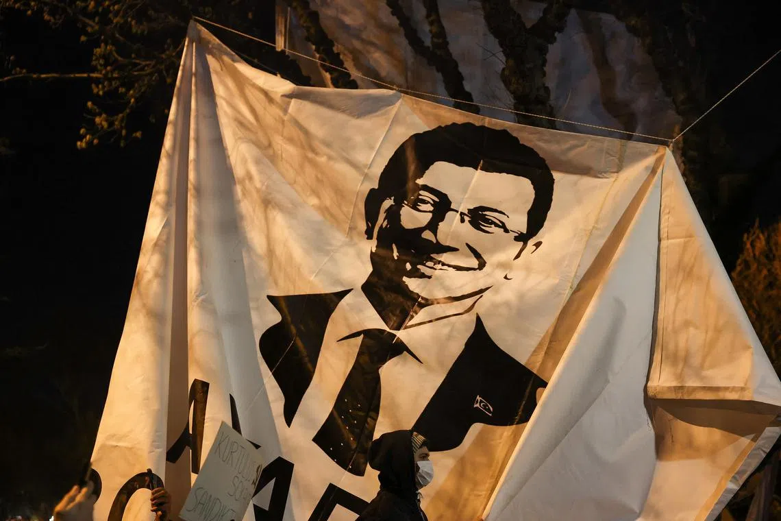 A person walks past a banner with an image of Istanbul Mayor Ekrem Imamoglu, as people take part in a protest against the detention of Imamoglu, in Istanbul, Turkey, March 20, 2025. REUTERS/Umit Bektas